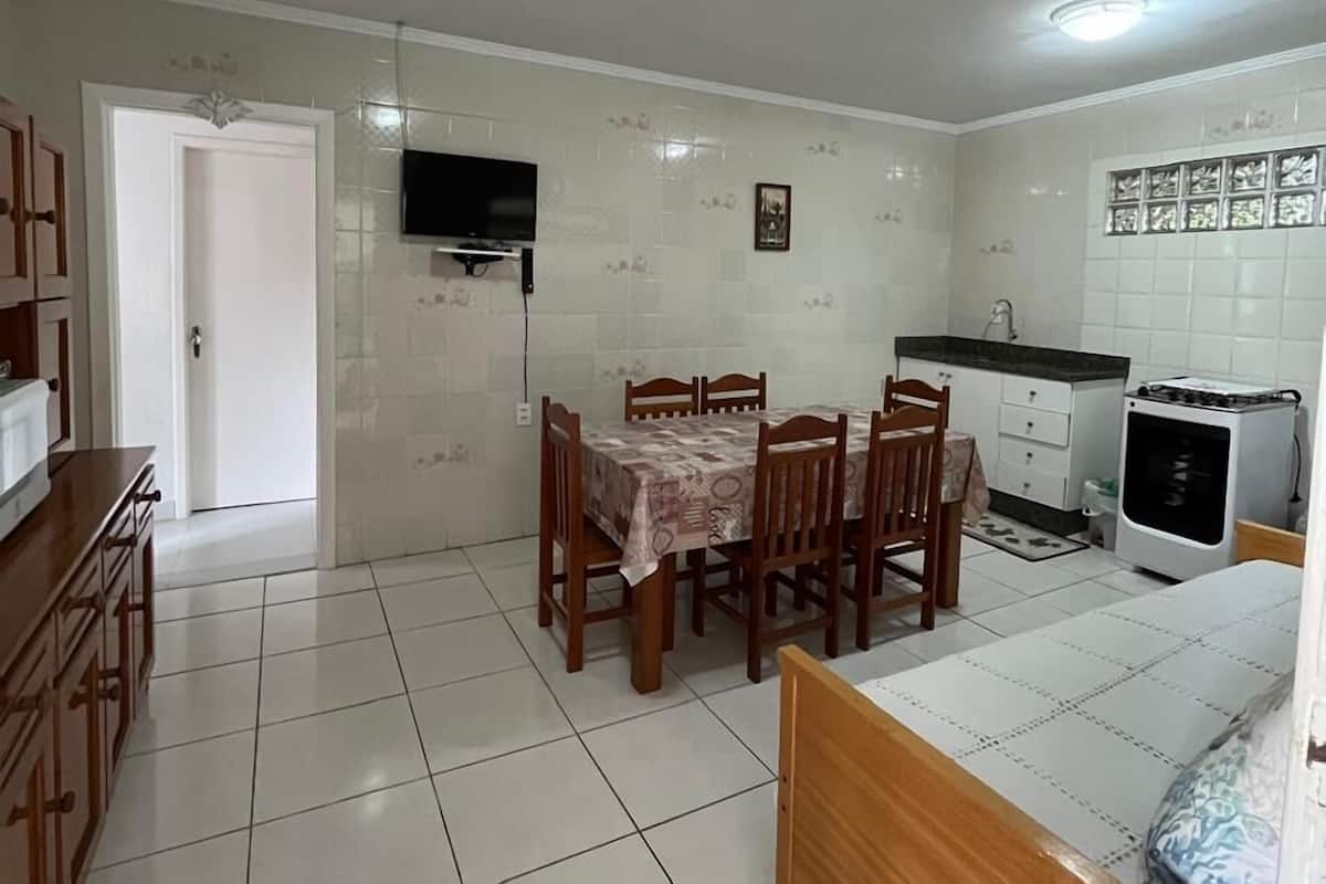 A compact kitchen with a dining area, a TV mounted on the wall, and a small refrigerator.