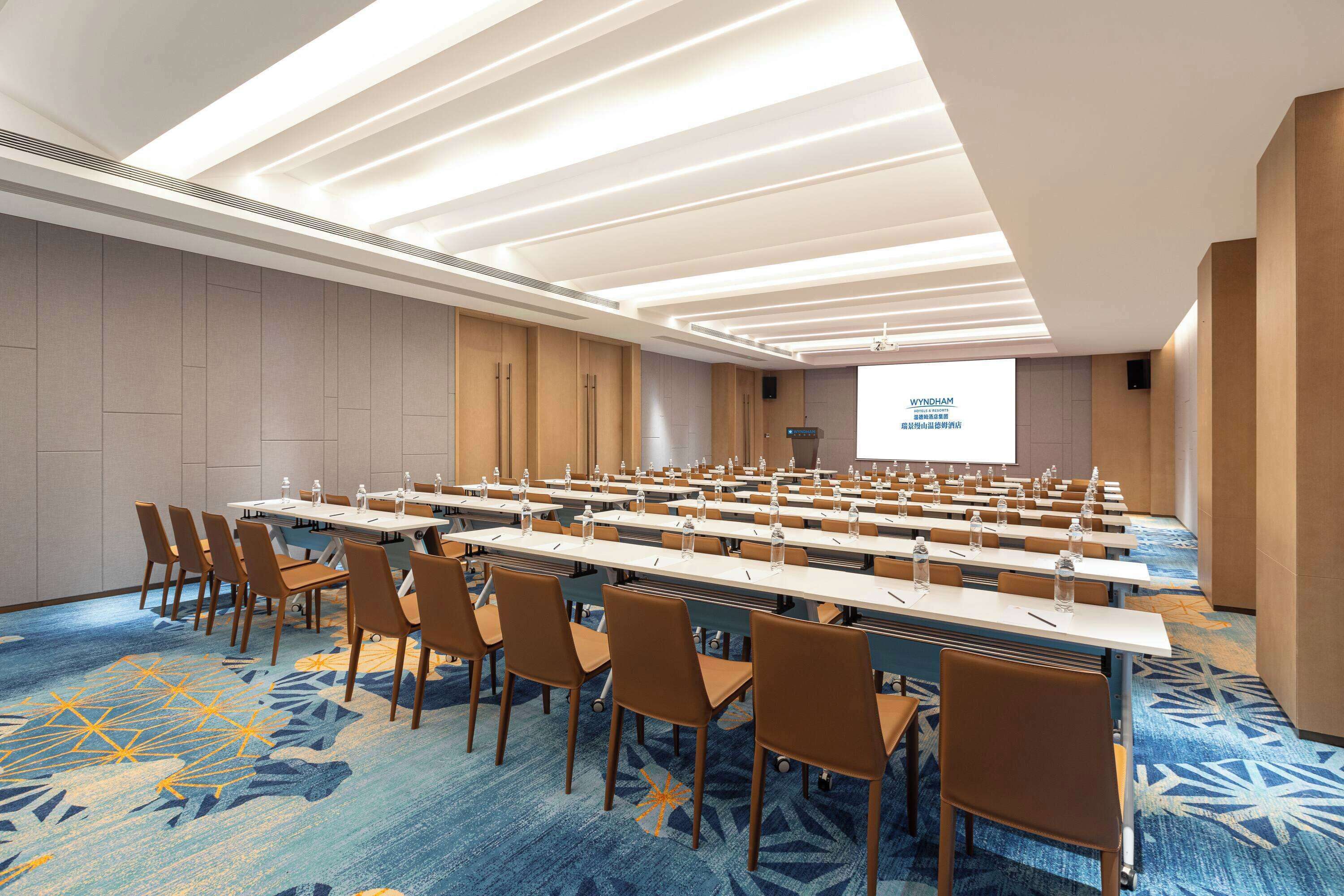 A conference room with long tables, chairs, and a presentation screen.