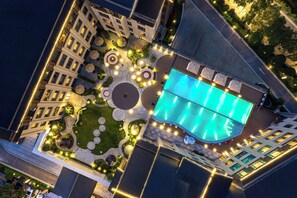 Ein Luftbild eines Hotels mit Swimmingpool, angelegten Gärten und gut beleuchteten Wegen.