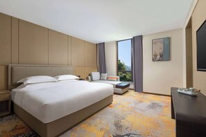A hotel room with a large bed, a sofa, a small table, and a TV.