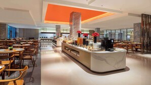 A modern hotel lobby with a central bar area, multiple dining tables, and a spacious layout. - Wyndham Zhangjiajie Wulingyuan (Zhangjiajie)