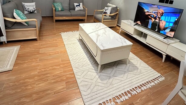 A modern living room with a sofa, armchairs, a coffee table, and a TV. - Nsiimenta Stay (Kampala)