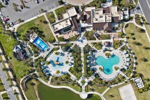 An aerial view of a resort with multiple swimming pools, a children's play area, and a variety of outdoor seating areas.