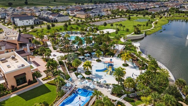 Vista aérea de una zona residencial con piscina, toboganes acuáticos y un lago.