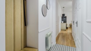 Een gang met een radiator, een spiegel en een deur.