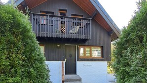 Ein zweistöckiges Gebäude mit Balkon, Steinstufen und Holztür.