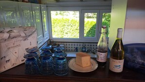Eine Küchenarbeitsplatte mit Käse, Weinflaschen und blauen Glasbehältern.