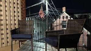 A balcony with wicker chairs and a metal railing.