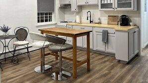 A modern kitchen with white cabinets, a wooden dining table, and a bar stool.