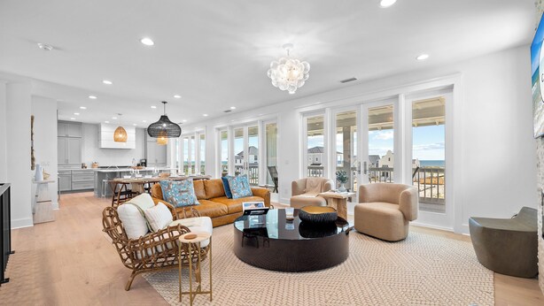 A spacious living room with a large window, a round coffee table, and a sofa. - Casa Feliz: Community Pool and Gym, Fire Pit (Mexico Beach)