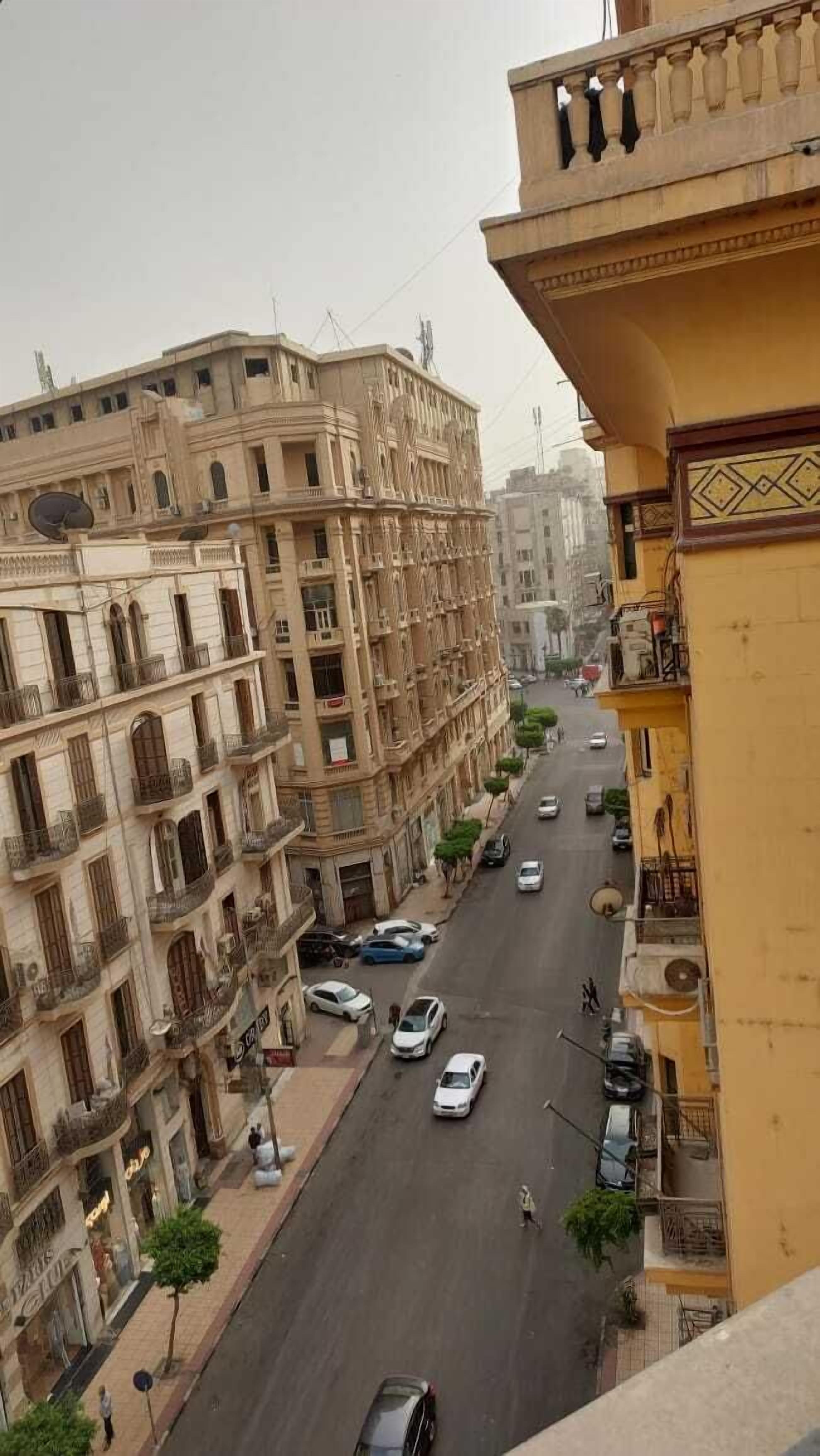 Vista de la calle con edificios altos, automóviles y peatones.