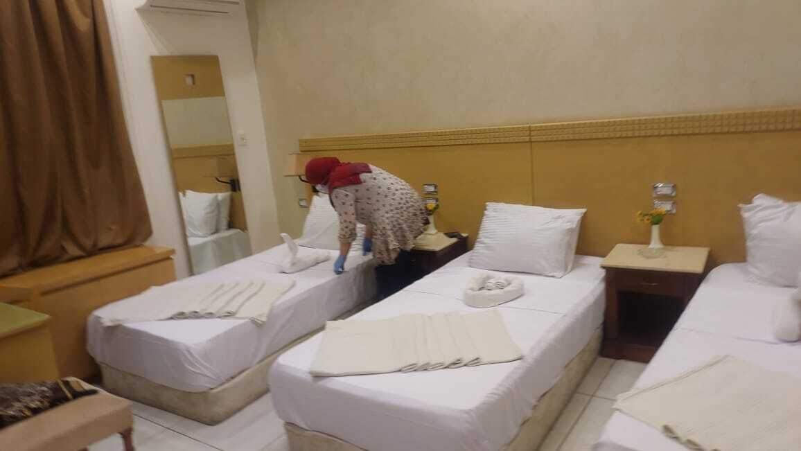 A hotel room with two beds, a bathroom, and a small table.