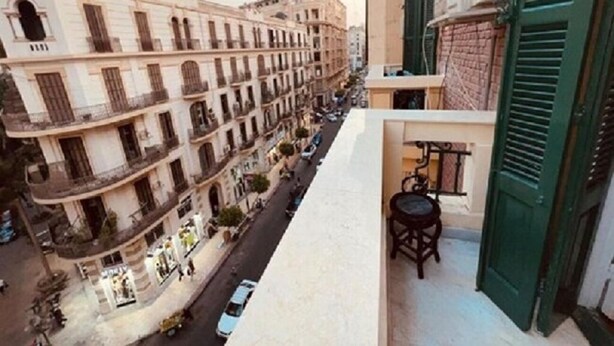 Un balcon donnant sur une rue bordée d’immeubles à étages multiples.