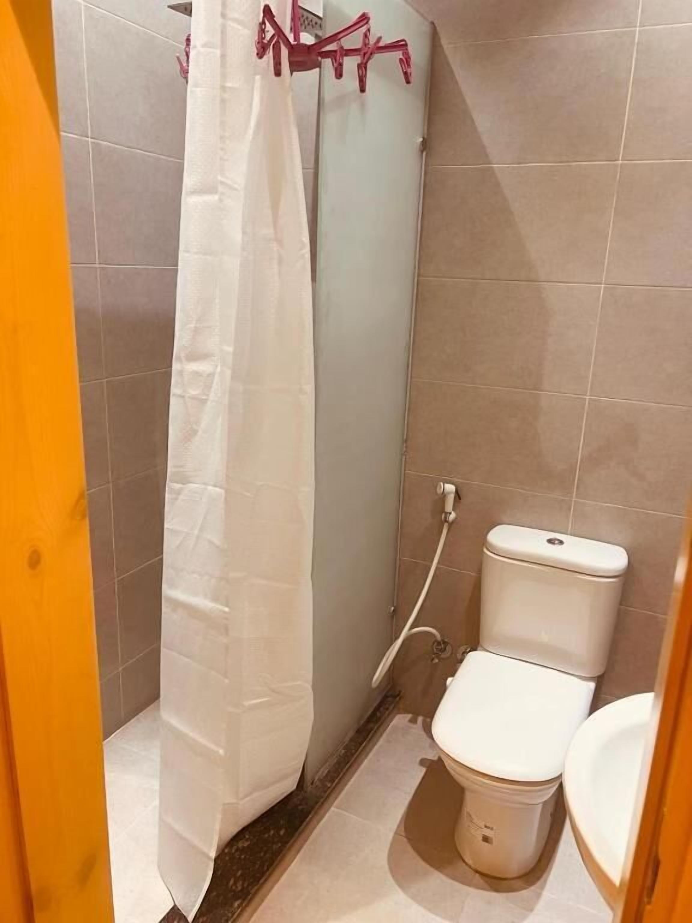 A small bathroom with a toilet, a shower, and a curtain.