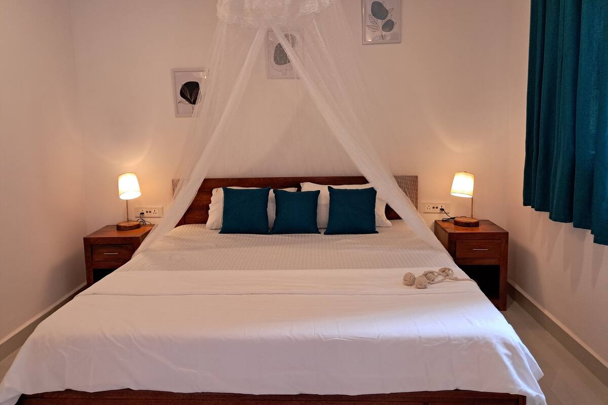 A neatly made bed with a canopy, two bedside lamps, and a small decorative item on the bed.
