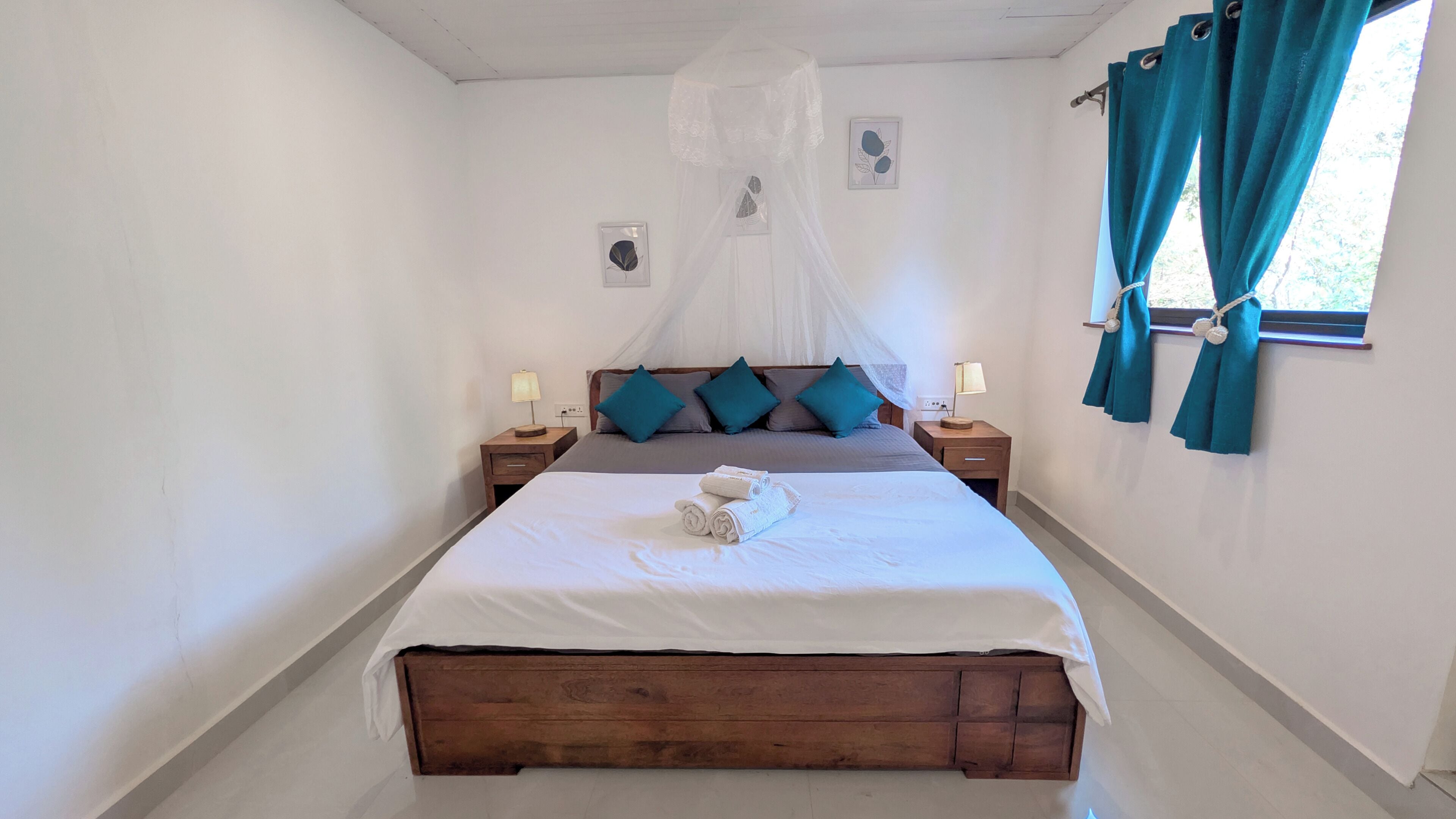 A bedroom with a wooden bed, a canopy, teal pillows, and a window with curtains.