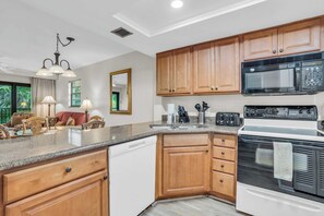 A kitchen with wooden cabinets, a microwave, a stove, and a dishwasher.