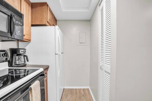 A compact kitchen with a microwave, coffee maker, stove, and refrigerator. - C-224 - End Unit with Private Views & Sleeps 6 (Naples)