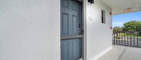A building entrance with a dark blue door, a white wall, and a small window.