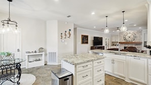 A modern kitchen with white cabinetry, granite countertops, and pendant lighting. - Vista Valley Vacay, 5-BD w Pool & Cinema (Lewisville)
