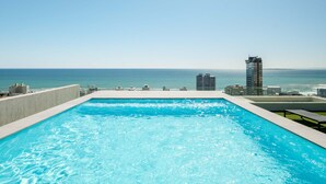 A rooftop infinity pool with a clear view of the ocean and distant buildings. - Charming Coastal Escape Marula One (Cape Town)