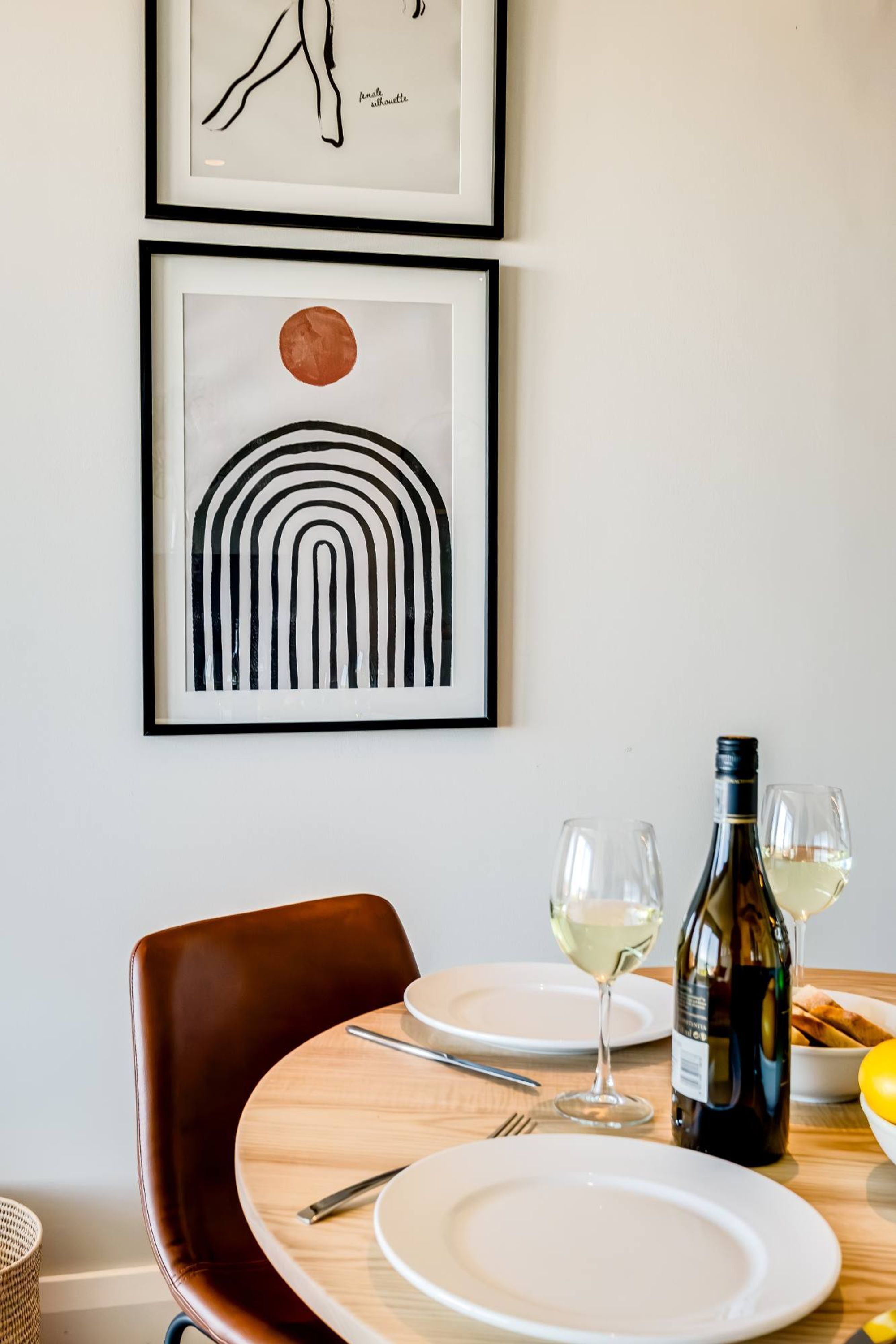 Een eettafel met borden, bestek en een fles witte wijn.