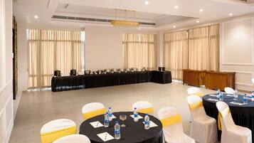 A conference room with round tables, chairs, and a long table with a black tablecloth.