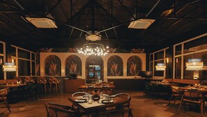 A spacious restaurant with high ceilings, large windows, and a central dining area with tables and chairs. - Silver Oak Tropical Resort By Bay Hotels (Uran)