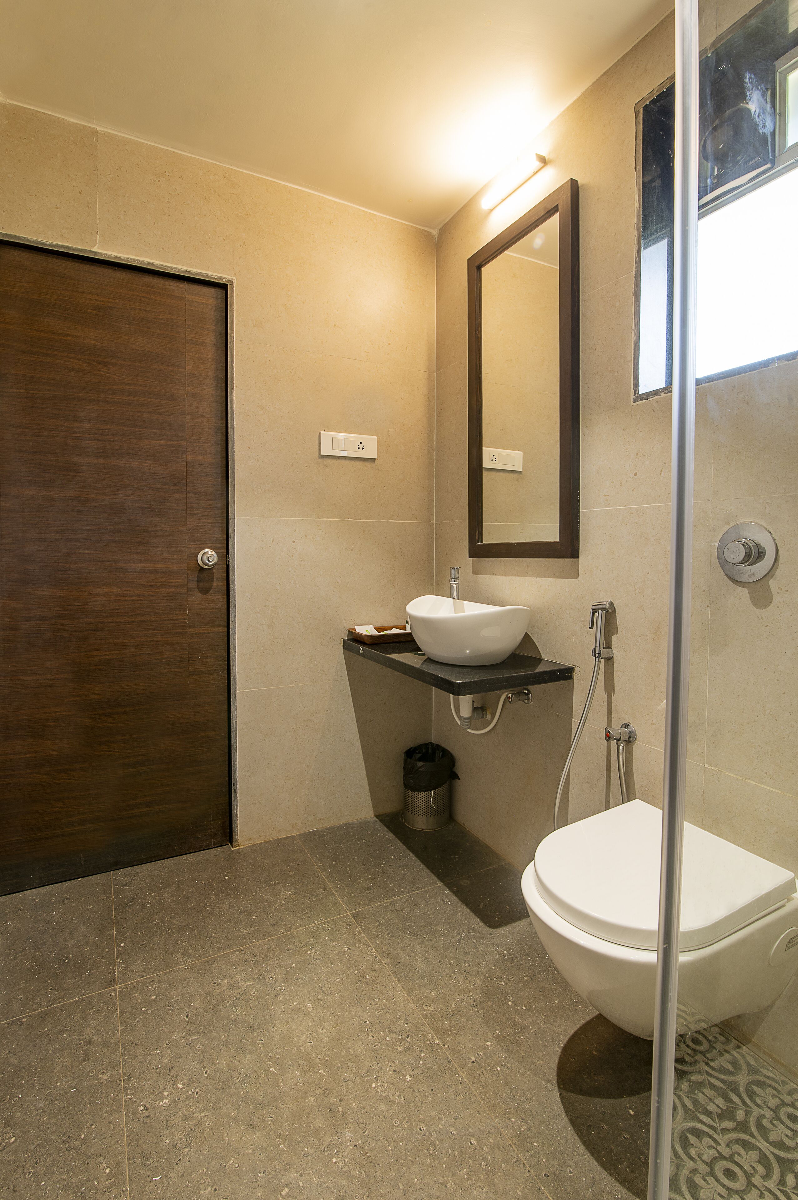 A bathroom with a wooden door, a white sink, a mirror, and a shower.