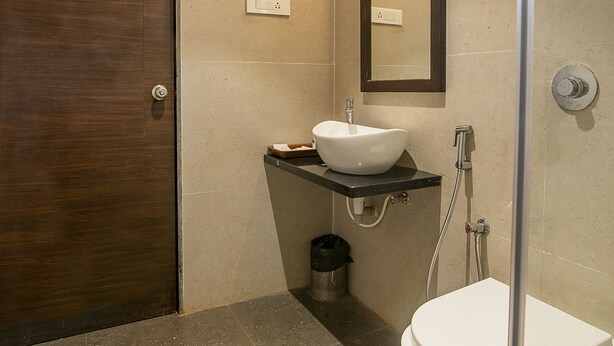 Un baño con puerta de madera, un lavabo blanco, un espejo y una ducha.