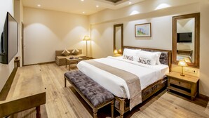 A bedroom with a large bed, bedside tables, a bench, a TV, and a lamp. - Silver Oak Tropical Resort By Bay Hotels (Uran)