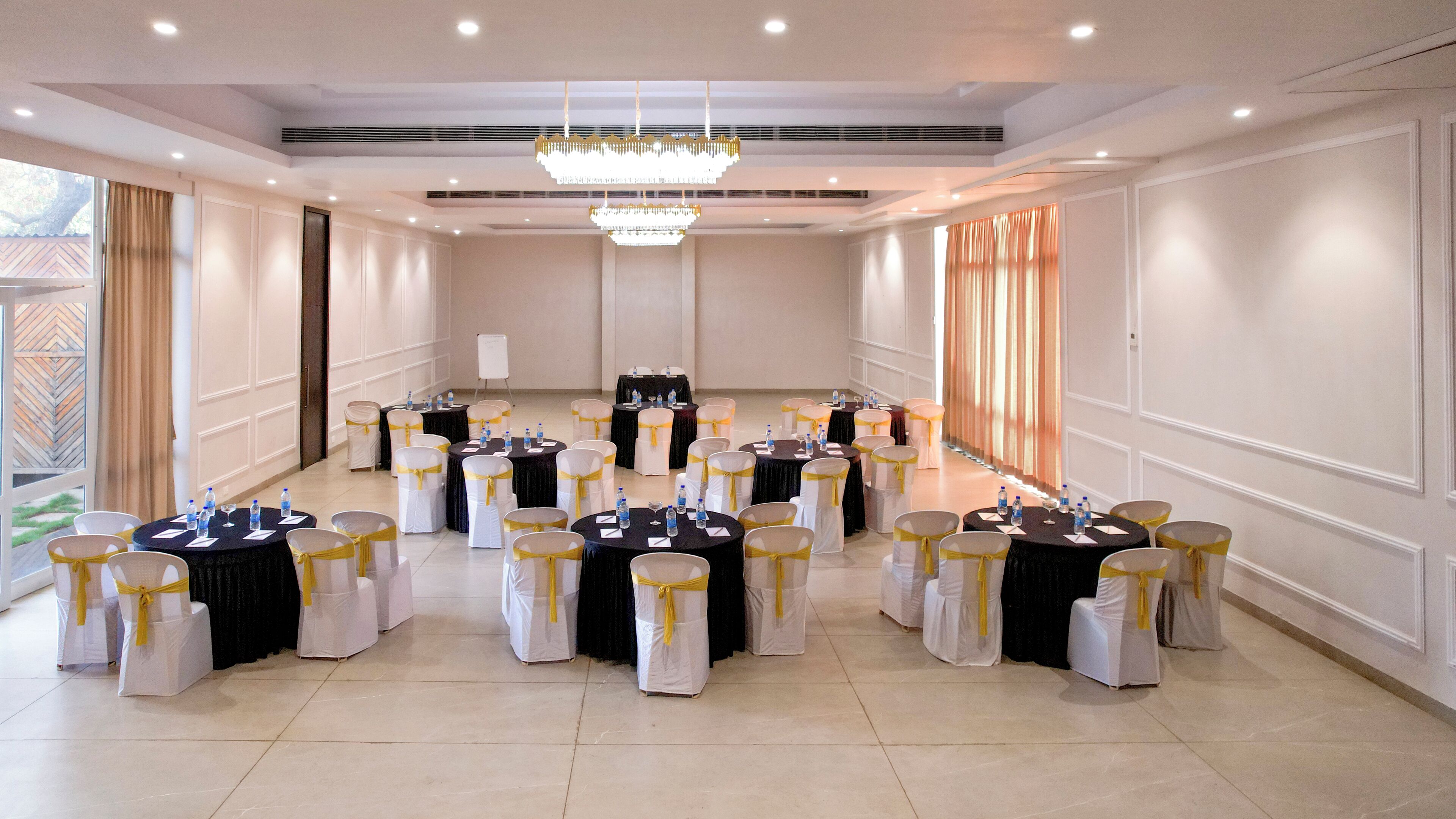 A conference room with round tables, chairs, and a chandelier.