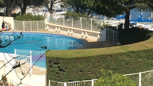 Una piscina circondata da una recinzione, con alberi e una vista sulle barche sullo sfondo.