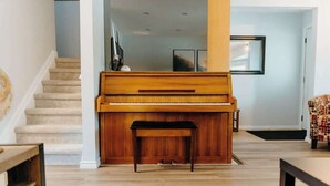Ein Klavier in einem Wohnzimmer mit einer Treppe im Hintergrund.