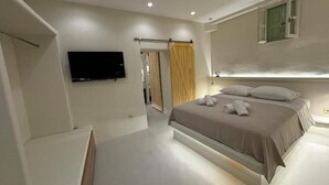 Une chambre à coucher moderne avec un grand lit, un téléviseur à écran plat fixé au mur et un placard à portes coulissantes.