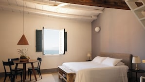 Une chambre à coucher avec un lit, un bureau avec des chaises, une fenêtre et une lampe.