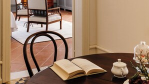 Un coin repas avec une table en bois, un livre ouvert, une théière et un vase de fleurs.