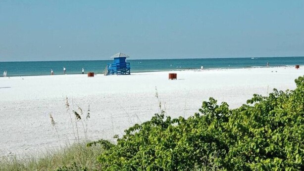 Una spiaggia con una torretta di salvataggio e un cielo sereno.