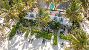A resort with multiple buildings, palm trees, and a pool. - Surfescape Zanzibar (Kiwengwa)
