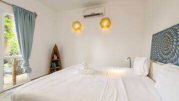Habitación de hotel con una cama grande, una estantería, un equipo de aire acondicionado y una ventana con cortinas.