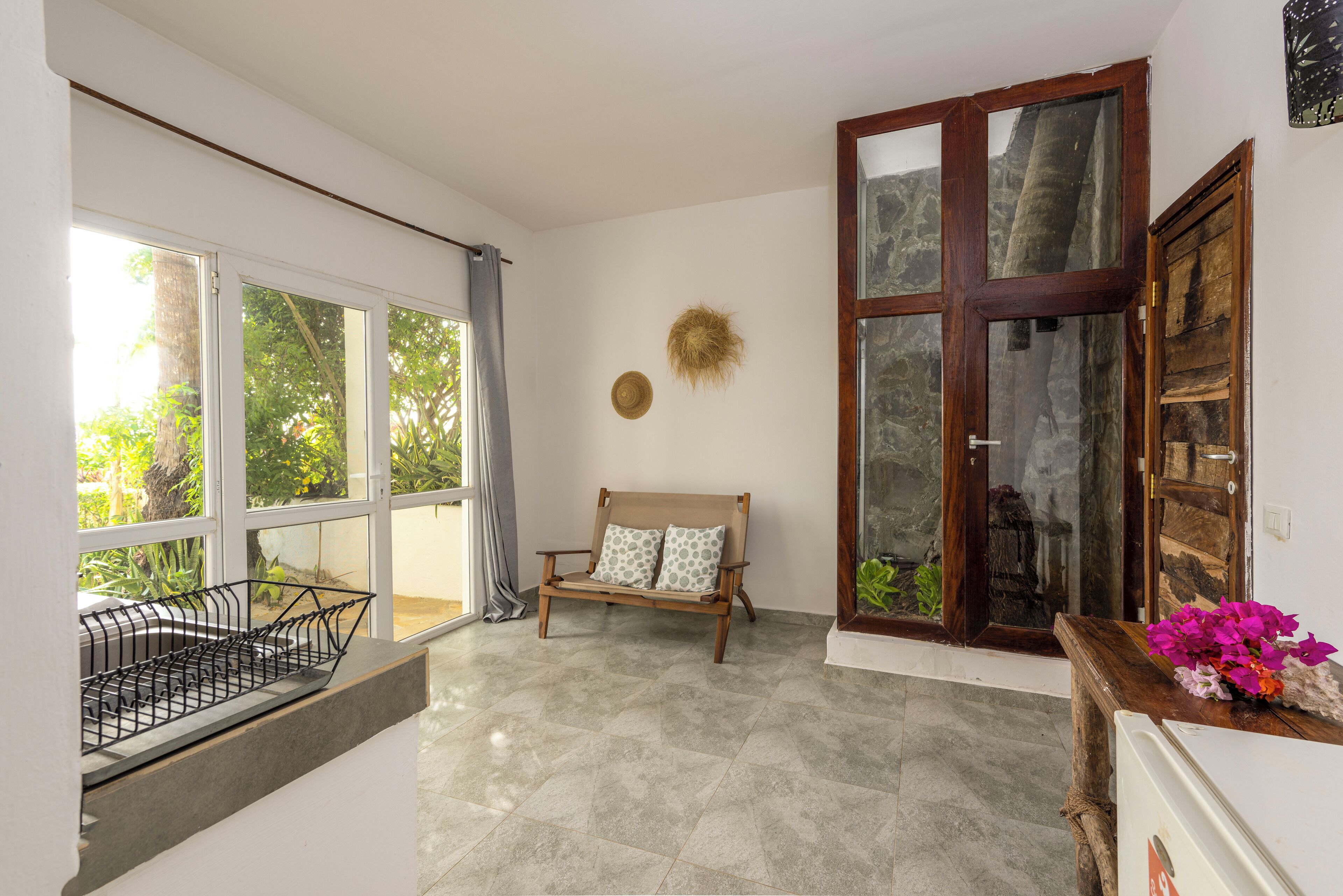 A room with a large window, a wooden bench, and a door with glass panels.