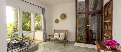 A room with a large window, a wooden bench, and a door with glass panels.