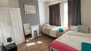 Een slaapkamer met twee bedden, een garderobe, een spiegel, een open haard en een schilderij aan de muur.