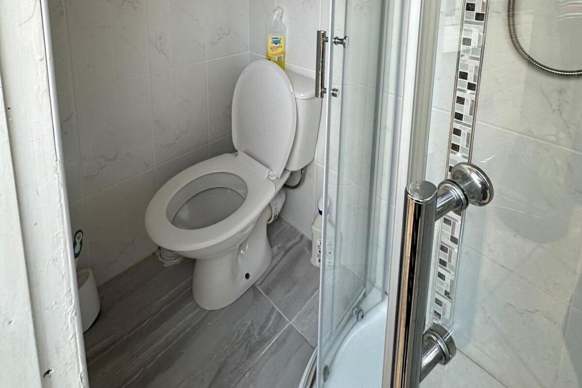 A modern bathroom with a toilet, a shower enclosure, and a toilet paper dispenser.