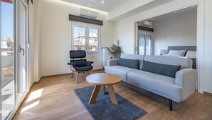 A modern living room with a sofa, a round coffee table, and a black chair. - Attiki Square & Metro Modern 2-Bedroom Apt by MPS (Athina)