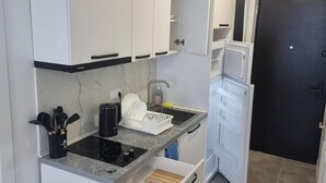 A compact kitchen with white cabinets, a built-in oven, a sink, and a microwave.