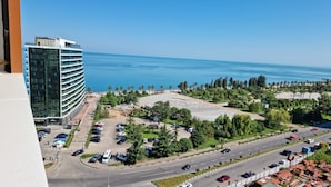 A high-rise hotel with a parking lot and a view of the sea.