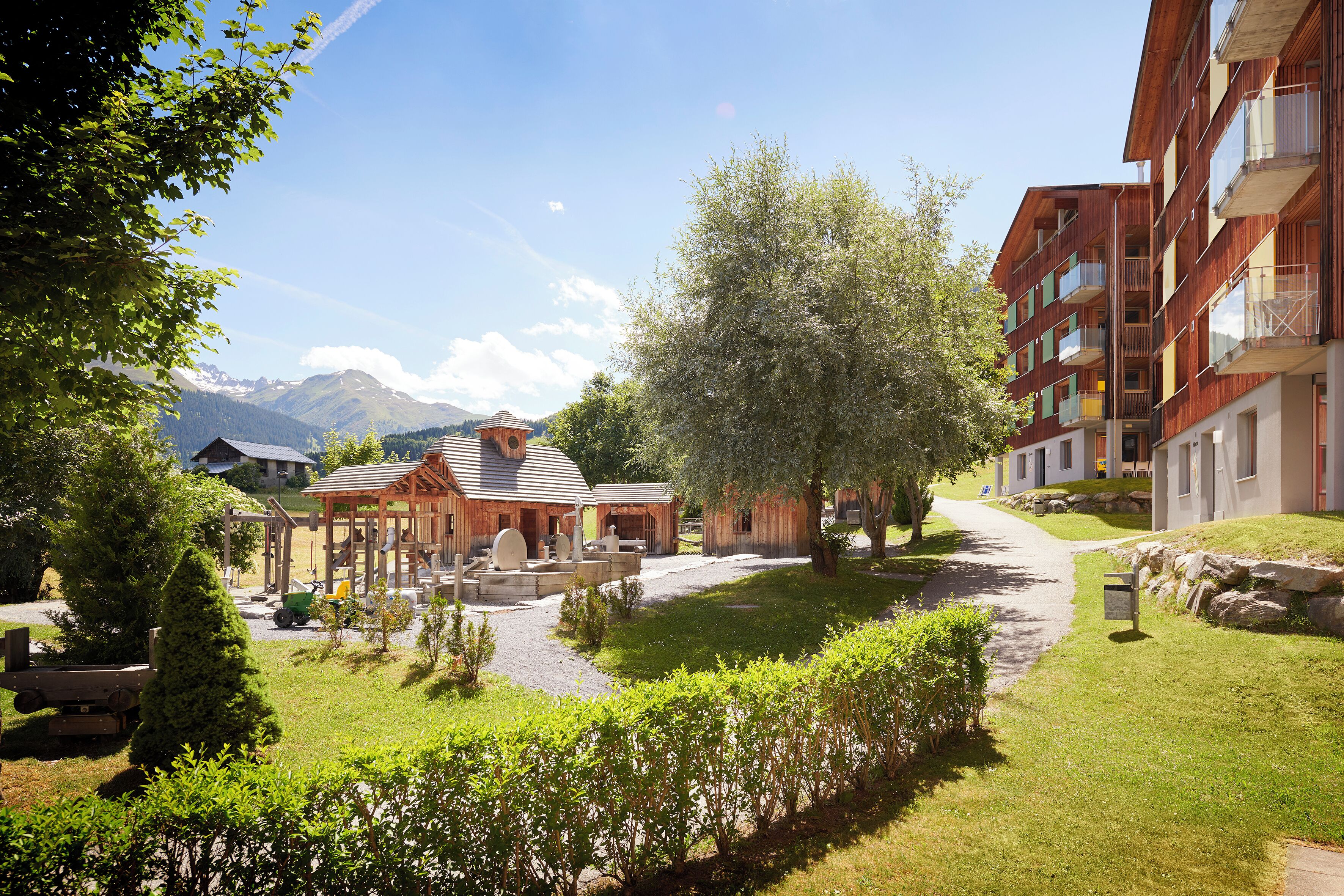Zona residencial con edificios de madera, un camino pavimentado y vistas a montañas.
