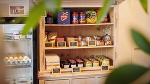 A wooden display case with various food items including jars of preserves and packaged goods. - Reka-Feriendorf Disentis (Disentis)
