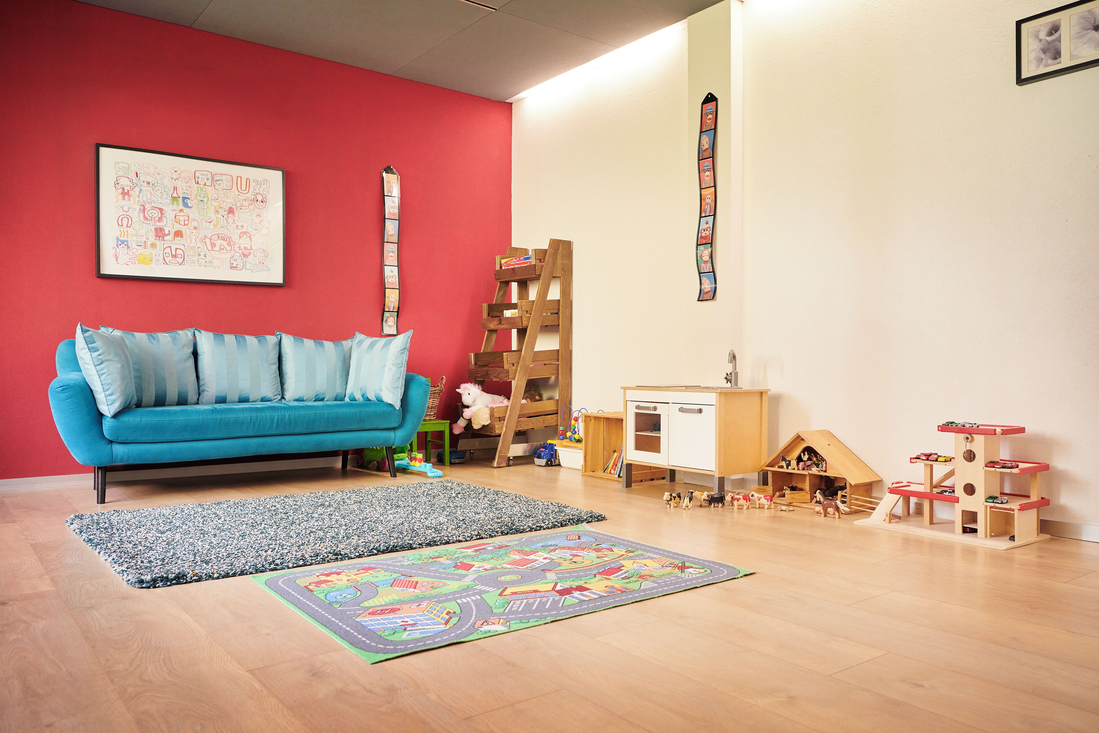A room with a blue sofa, a wooden ladder, a playhouse, and a colorful rug.